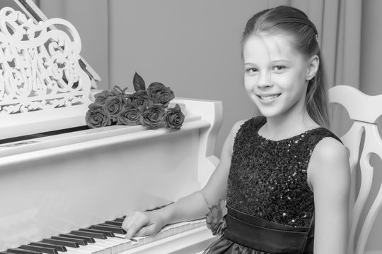 Little girl plays the piano, black and white photo.