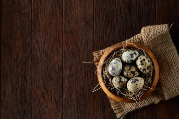 Rustic still life with quail eggs in bucket, box and bowl on a linen napkin over wooden background, selective focus