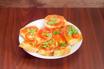 Sandwiches made with salted salmon on dish on wooden table