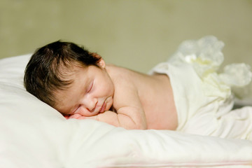 Fototapeta na wymiar A newborn infant, the baby is sleeping lying on his stomach on a soft blanket