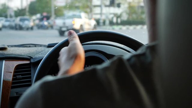 slow motion, man hand control steering wheel driving car turn right on crossroad with green traffic light in town