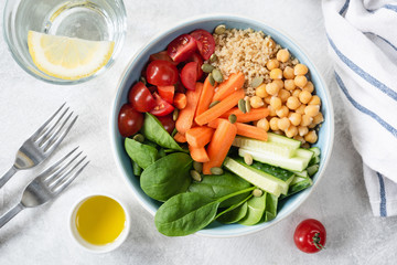Top view of Salad bowl with quinoa, chickpeas, cucumber, baby carrots, spinach and tomatoes. Concept of healthy eating, healthy lifestyle, detox diet, vegan and vegetarian food
