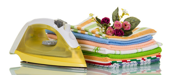 Pile of clean ironed linen and electric iron, isolated on white