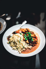 Marokkanisches Hühnchen mit Pflaumen, Mandeln und tomaten, angerichtet auf CousCous mit frischer petersilie 