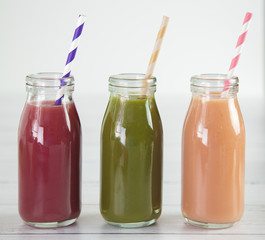 Three Different Fruit Smoothy on a White Wood Table - Berry, Green, and Strawberry Banana