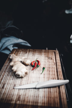 Holzbrett aus Bambus mit Ingwer und Chilli neben einem Messer