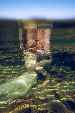 Bride and groom embracing under water