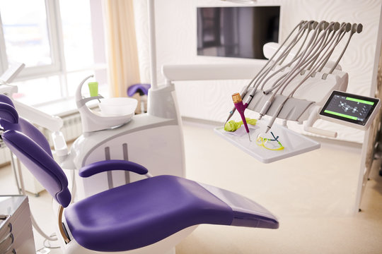 Background image of empty dentists office with purple dental chair, copy space
