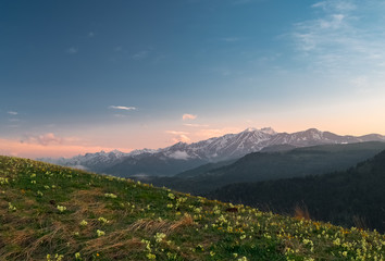Fototapeta na wymiar mountain ranges of the Karachay-Cherkess Republic with clouds at sunset with a green meadow with flowers