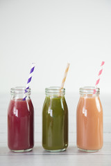 Three Different Fruit Smoothy on a White Wood Table - Berry, Green, and Strawberry Banana