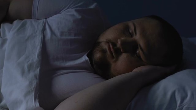 Overweight man sleeping in bed at night, resting on comfortable pillow, dreams