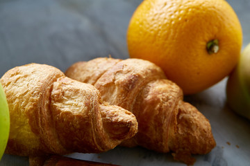 Breakfast served with croissants and fruits, top view, close-up, selective focus