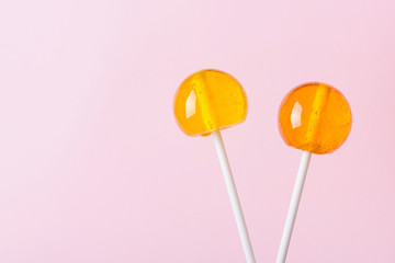 Two lollipops on white plastic sticks on pink pastel background with copy space