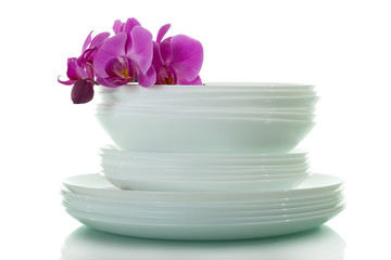 Stack of clean plates, upper Orchid flower isolated on white