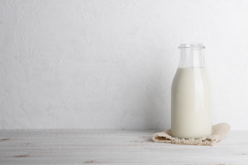 Bottle of milk on a sack cloth on white wooden table background horizontal with copy space