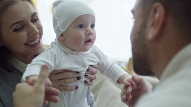 Medium shot of happy young parents playing with laughing baby boy