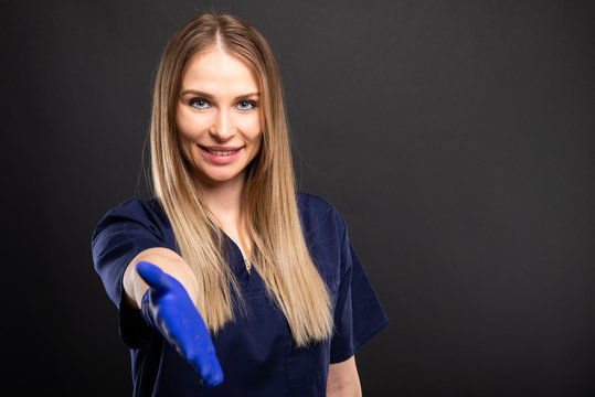 Female dentist wearing scrubs showing offering hand shake.