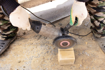 A man cuts a brick at a construction site