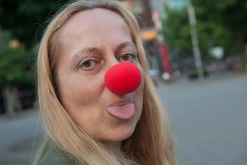 Woman with clown nose making a joke and sticking out her tongue