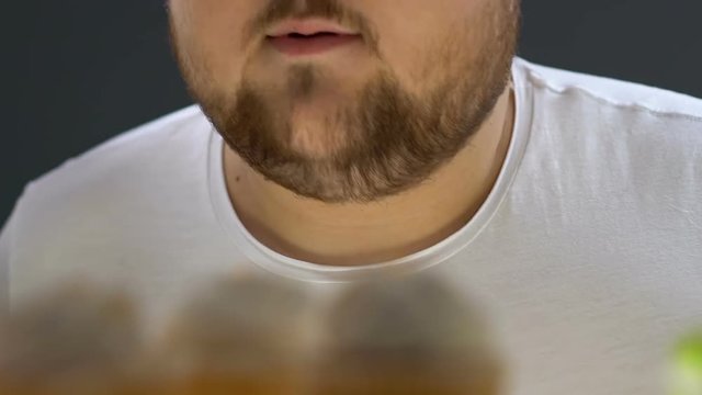 Obese addicted man opening fridge, eating delicious whipped cream on top of cake