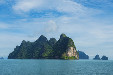 Three boats sailing through tropical group of islands with limestone caves inside in Ao Phang-Nga National Park, Andaman Sea, Thailand.