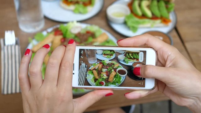 Woman Hands Holding Cellphone And Taking Picture Of Vegan Food.