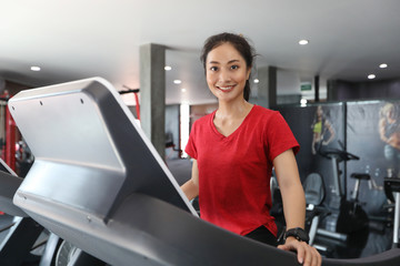 Fototapeta na wymiar Asian women running sport shoes at the gym while a young caucasian woman is having jogging on the treadmill
