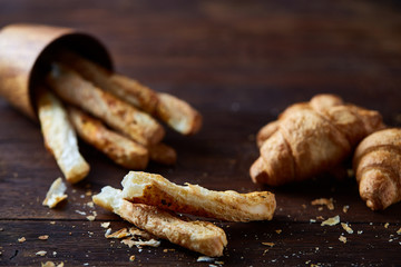 Delicious breadsticks grissini on wooden dark background in overturned wooden oldstyle cup, close-up, selective focus