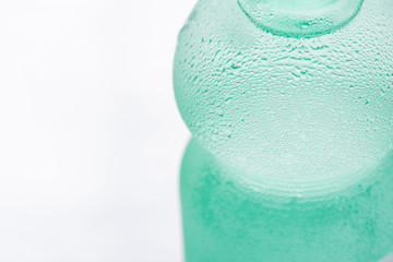 Light Green Sweated Frosty Bottle with Clear Pure Cool Water on White Background. Hydration Summer Refreshment Minerals Health Concept. Copy Space