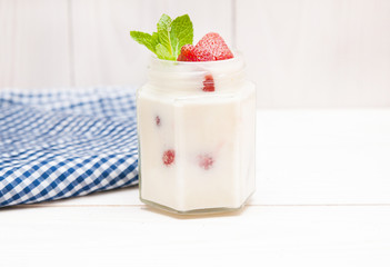 Cream with a strawberry on white wooden background.
