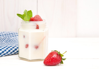 Cream with a strawberry on white wooden background.
