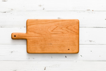 Handmade cherry wooden chopping board on a white wooden board desktop
