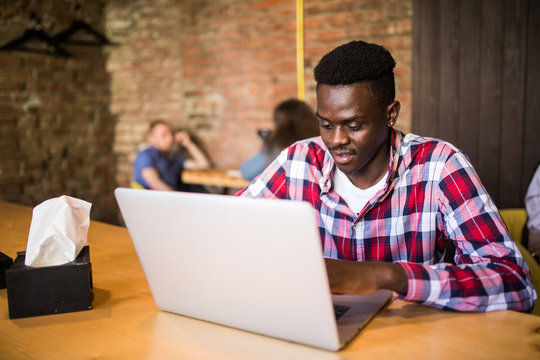 Portrait of african american man sitting at a cafe and working on a laptop.