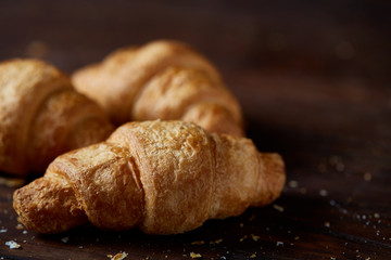 Tasty buttery croissants on an old wooden table, close-up, selective focus, shallow depth of field.