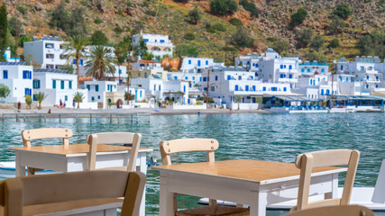 Fototapeta na wymiar Restaurant tables with view on the scenic village of Loutro in Crete, Greece