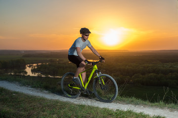 Obraz premium A cyclist in a white T-shirt rides a bike along the mountain path. The concept of extreme sports. Mountain bike.