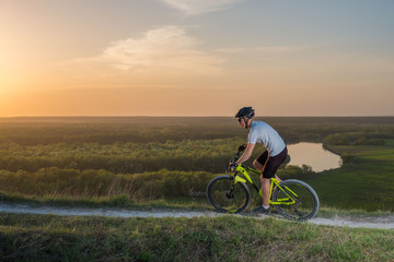 A cyclist in a white T-shirt rides a bike along the mountain path. The concept of extreme sports. Mountain bike.