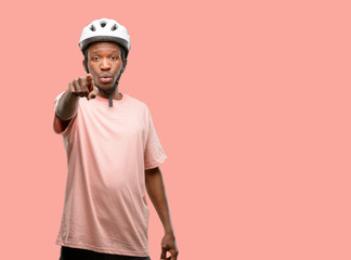 Black man wearing bike helmet pointing to the front with finger