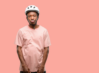 Black man wearing bike helmet with sleepy expression, being overworked and tired