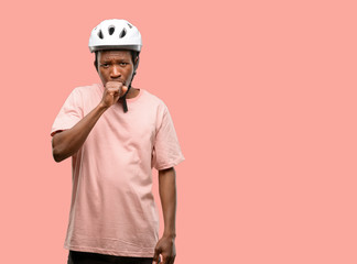Black man wearing bike helmet sick and coughing, suffering asthma or bronchitis, medicine concept