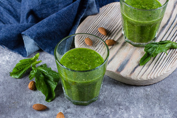 Blended Green Smoothie with green apple, spinach, kiwi and almond nuts on gray concrete background. Food and drink, healthy lifestyle, diet and nutrition concept.