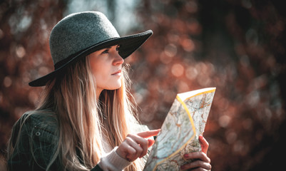 Hipster stylish tourist woman in hat with map, sunny day in forest