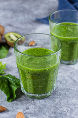 Blended Green Smoothie with green apple, spinach, kiwi and almond nuts on gray concrete background. Food and drink, healthy lifestyle, diet and nutrition concept.