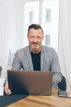 Smiling mature man sitting in front of computer