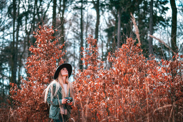 Beautiful girl with vintage camera in golden autumn forest