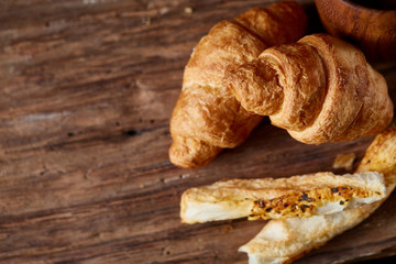 Puff pastries on piece of board over dark wooden table, close-up, selective focus, backlight.