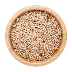 Raw organic green buckwheat grains in wooden bowl isolated on white. Top view.
