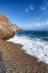 Sea waves crashing on the shore and flowing above seashore pebbles
