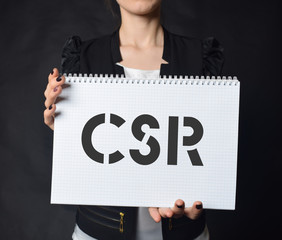 In the hands of a businessman a notebook with the inscription:CSR