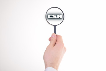 Businessman looking at a magnifying glass word:CSR